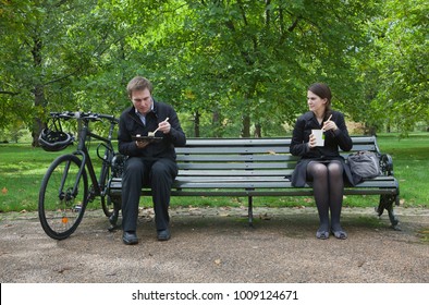 Woman And Man Eating Lunch On Park Bench