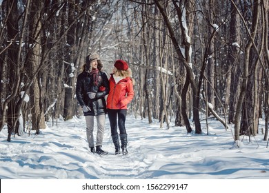 Woman And Man Enjoying Winter In The Snow Having A Walk In The Forest