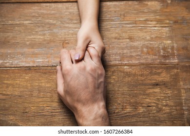 woman and man hand in hand on the wooden desk - Shutterstock ID 1607266384