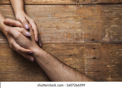woman and man hand in hand on the wooden desk - Shutterstock ID 1607266399
