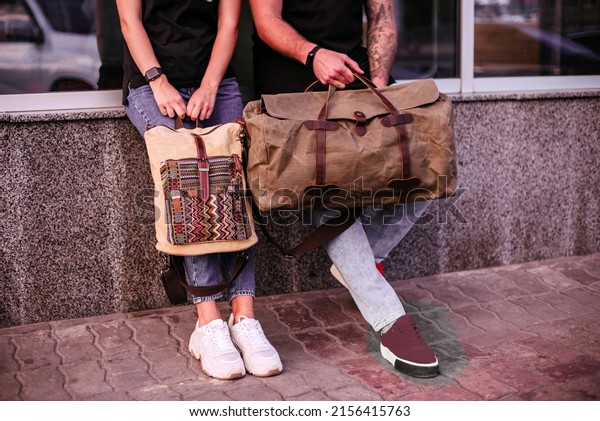 Woman and man holding canvas bags. Backpack and\
duffel canvas bag
