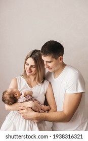 Woman And Man Holding A Newborn. Mom, Dad And Baby. Close-up. Portrait Of Young Smiling Family With Newborn On The Hands. Happy Family On A Background. 