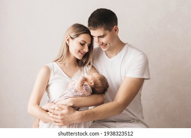 Woman And Man Holding A Newborn. Mom, Dad And Baby. Close-up. Portrait Of Young Smiling Family With Newborn On The Hands. Happy Family On A Background. 