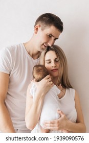 Woman And Man Holding A Newborn. Mom, Dad And Baby. Close-up. Portrait Of Young Smiling Family With Newborn On The Hands. Happy Family On A Background. 