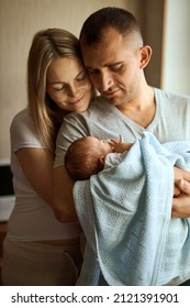 Woman And Man Holding A Newborn. Mom, Dad And Baby. Close-up. Portrait Of Young Smiling Family With Newborn On The Hands.