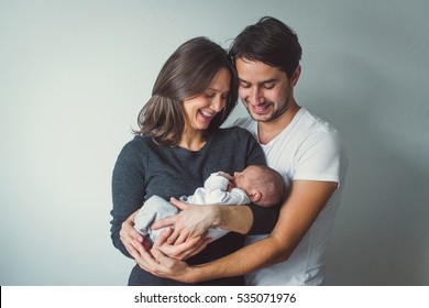 Woman and man holding a newborn. Mom, dad and baby. Close-up. Portrait of young smiling family with newborn on the hands. Happy family on a background.  - Shutterstock ID 535071976