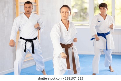 Woman and man in kimono standing in fight stance during group karate training