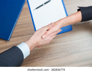 Woman And Man Shaking Hands Over Paper And Pen On The Table.