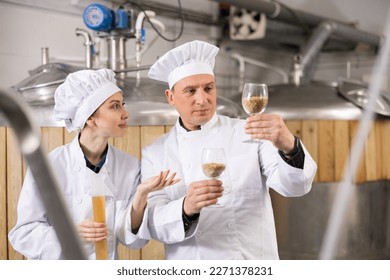 Woman and man skilled brewers checking quality of raw materials while standing in brewery carefully examining malted grain.. - Shutterstock ID 2271378231