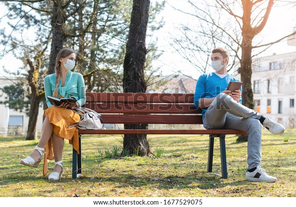 公園のベンチに座る 社会的に離れた男女 の写真素材 今すぐ編集