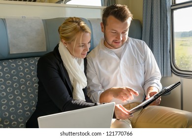 Woman and man in train laptop clipboard work commuting smiling