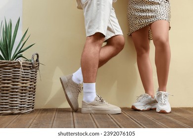 Mujer y hombre con zapatillas elegantes cerca de la pared beige, armario