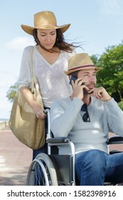 Woman And Man In Wheelchair Using Phone At The Park