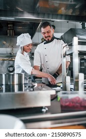 Woman And Man Woking Together. Professional Chef Preparing Food In The Kitchen.