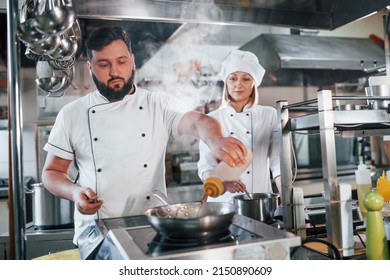 Woman And Man Woking Together. Professional Chef Preparing Food In The Kitchen.