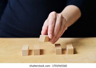 Woman manager builds a development strategy from wooden parts - conceptual business photography. Female hand stacking the wooden parts. - Shutterstock ID 1701965560