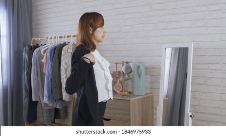 Woman Manager Shrugging On Black Suit Jacket And Fastening Button In Front Of Mirror At Home. Getting Ready For Work Concept. Genuine Lifestyle