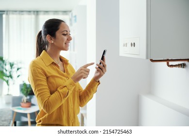 Mujer manejando y programando su caldera inteligente usando su concepto de smartphone, hogar inteligente
