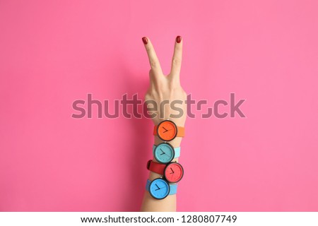 Woman with many bright wrist watches on color background, closeup. Fashion accessory