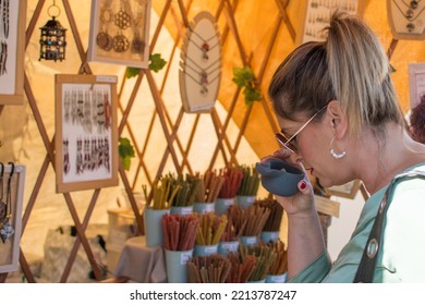 Woman In The Market.
Mature Woman In The Stalls Of A Street Market On A Street Choosing And Smelling Incense Sticks.