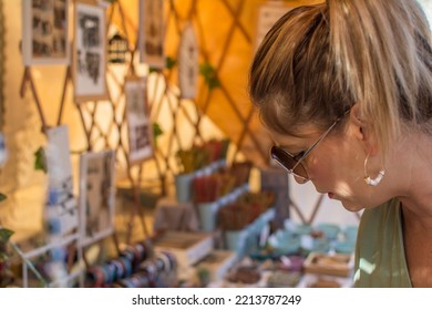 Woman In The Market.
Mature Woman In The Stalls Of A Street Market On A Street Choosing And Smelling Incense Sticks.