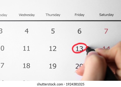 Woman marking Friday 13th on calendar, closeup. Bad luck superstition