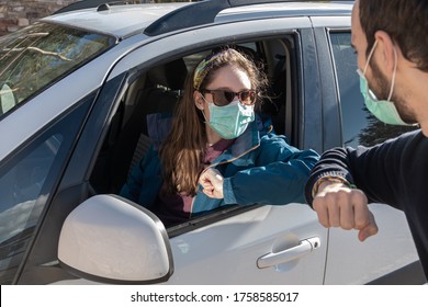 Woman With Mask From A Car Waving An Elbow To A Man During The Pandemic. New Normal