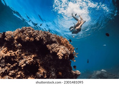 Woman with mask dive to the deep near corals in tropical blue sea. Snorkeling with woman in Hawaii