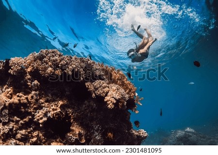 Woman with mask dive to the deep near corals in tropical blue sea. Snorkeling with woman in Hawaii