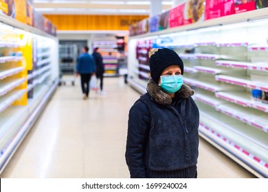 Eine Frau mit Maske sieht im Gang zwischen leeren Regalen in einem Supermarkt verwirrt aus.Gesichtsmaske zum Schutz vor der Ausbreitung von Coronavirus-Krankheit. In der Stadt kommt es zu einer Epidemie des Coronavirus.COVID-19 pandemischer Coronavirus.