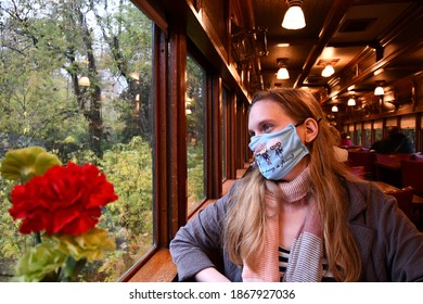 A Woman With A Mask On Her Face On A Train. She Is Looking Out A Window. There Are Flowers In The Corner. Picture Taken On October 19th, 2020 In Eureka Springs, Arkansas.