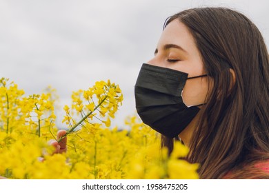 Woman With Mask In Rapeseed Field, Smelling Flowers. Space For Text