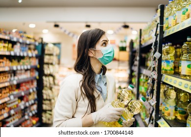 Woman With Mask Safely Shopping For Groceries Amid The Coronavirus Pandemic In Stocked Grocery Store.COVID-19 Food Buying In Supermarket.Panic Buying,stockpiling.Staples Shortage.Cooking Vegetable Oil