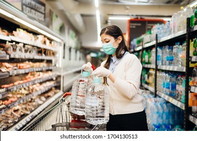 Woman With Mask Safely Shopping For Groceries Amid The Coronavirus Pandemic In A Stocked Grocery Store.COVID-19 Food Buying In Supermarket.Panic Buying,stockpiling.Lockdown Preparation.Water Shortage