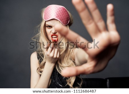    woman in mask for sleep colors lips holds hand in front of party                            