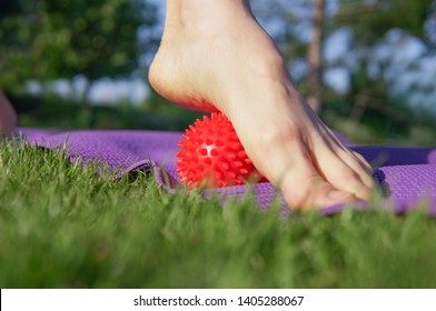 Woman massage feet with spiny plastic red massage ball in summer park. Self myofascial release concept, love your feet - Powered by Shutterstock