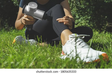 Woman massaging leg with massage percussion device after workout.