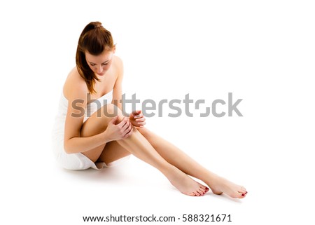 Woman massaging legs sitting on white background 