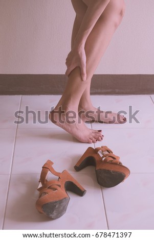Women wearing high heels brown shoes, massaging tired legs Women wearing high heels brown shoes, massaging tired legs