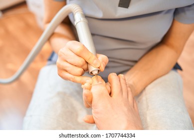 Woman Master Pedicures A Man. Hardware Pedicure. Leg Close Up. A Man Sits In A Pedicure Chair