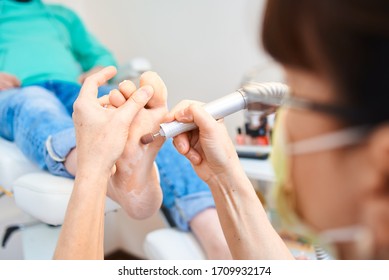 Woman Master Pedicures A Man. Hardware Pedicure. Leg Close Up. A Man Sits In A Pedicure Chair