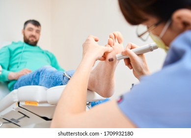 Woman Master Pedicures A Man. Hardware Pedicure. Leg Close Up. A Man Sits In A Pedicure Chair