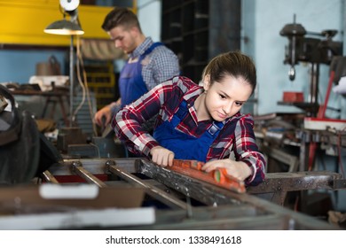 Woman master is standing near workplace and working with level in workshop - Powered by Shutterstock