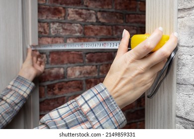 a woman measures a doorway in a house with a tape measure. High quality photo - Powered by Shutterstock