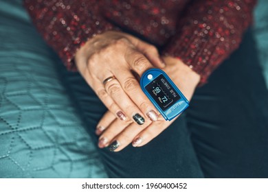 Woman measuring the degree of oxygen saturation of the blood and heart rate at home using pulse oximeter. Home treatment of virus. Checking health condition. Coronavirus pandemic. Covid-19 outbreak