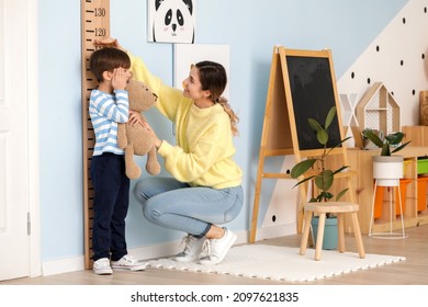 Woman Measuring Height Of Her Little Son At Home