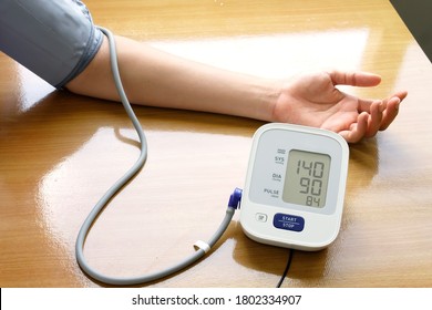 Woman Measuring Her Blood Pressure By Blood Pressure Monitor At Home. High Blood Pressure Concept.