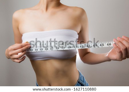 A woman measuring her bust with a measure.