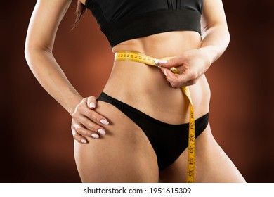 Woman with measuring her waistline. Healthy weight concept.
