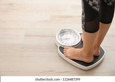 Woman measuring her weight using scales on wooden floor. Healthy diet - Shutterstock ID 1126487399